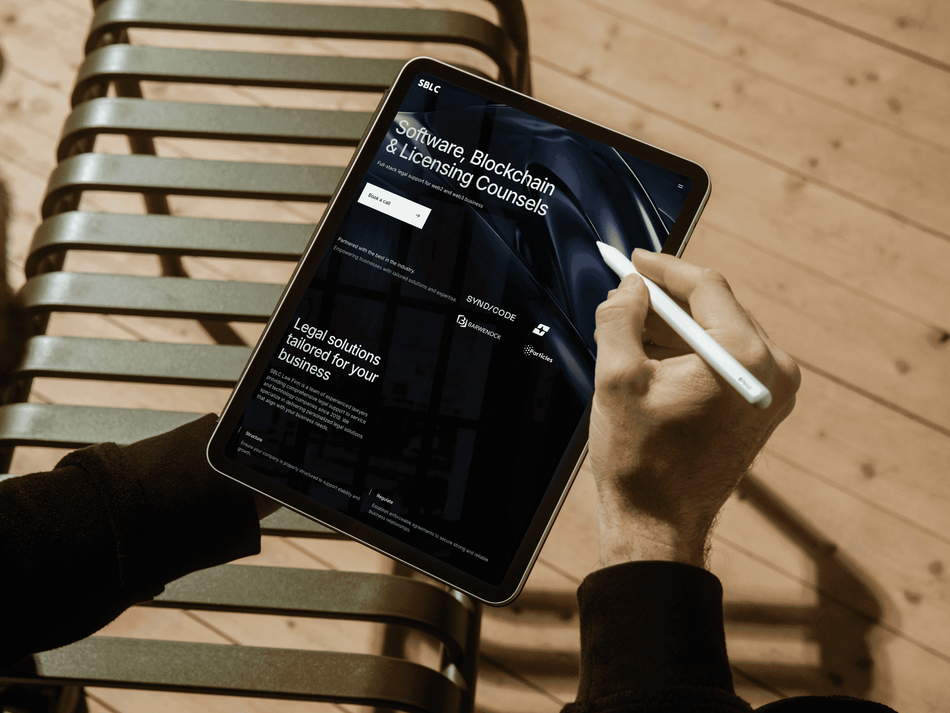 A person using a stylus on an iPad, navigating SBLC’s website with a modern and minimal UI.